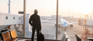 Blogs 3 Man is standing near window at the airport and watching plane before departure